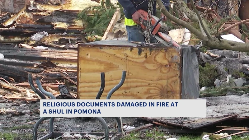 Story image: Religious leaders work to salvage sacred Torah scrolls after fire
