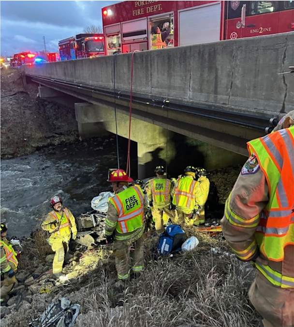 Fire department rescuers in reflective vests walk down the embankment. 